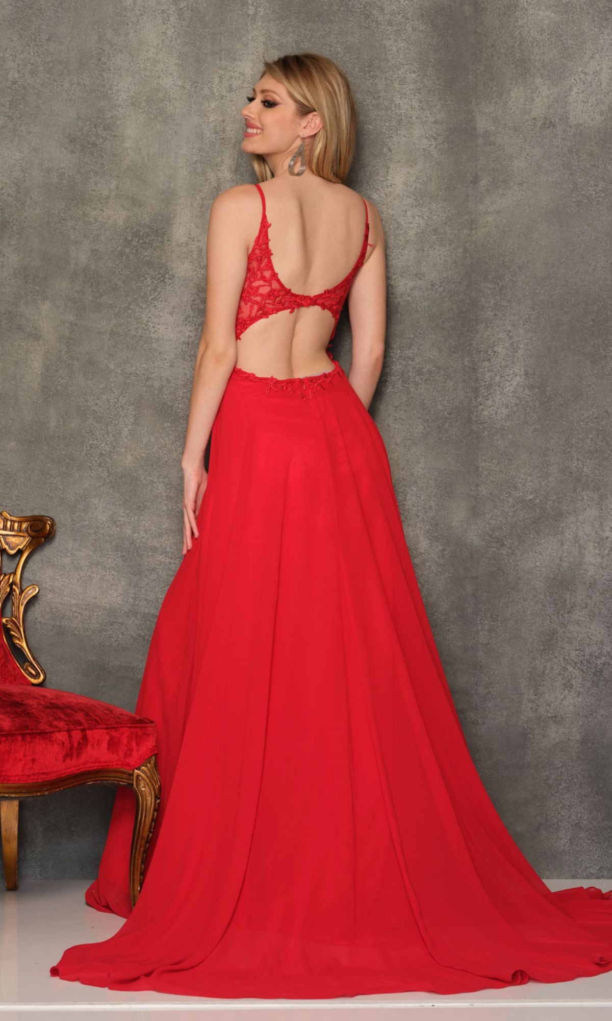 A woman wearing the Sheer-Bodice Dave & Johnny Long Prom Dress stands with her back to the camera beside an ornate red and gold chair.
